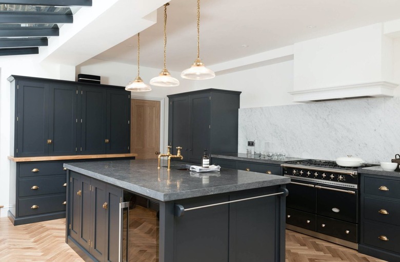 inky blue kitchen with carrara marble backsplash and limestone counters