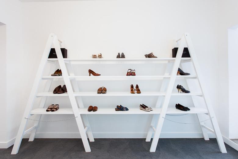 A white bookshelf against a white wall with shoes