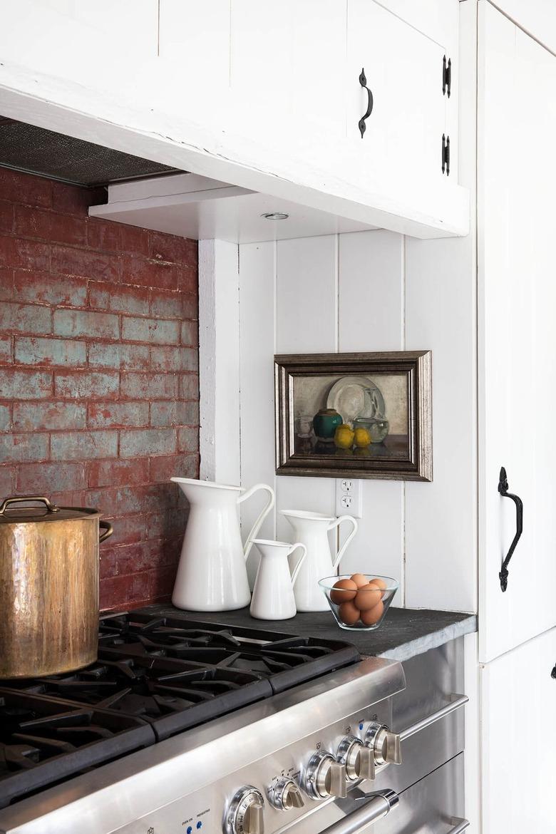 white kitchen with slate countertops and brick backsplash