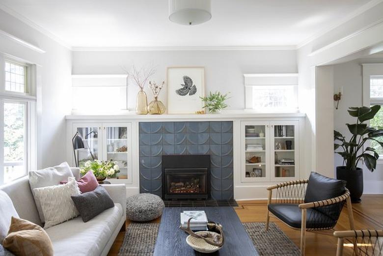 living room space in craftsman home with gray fireplace and green chairs