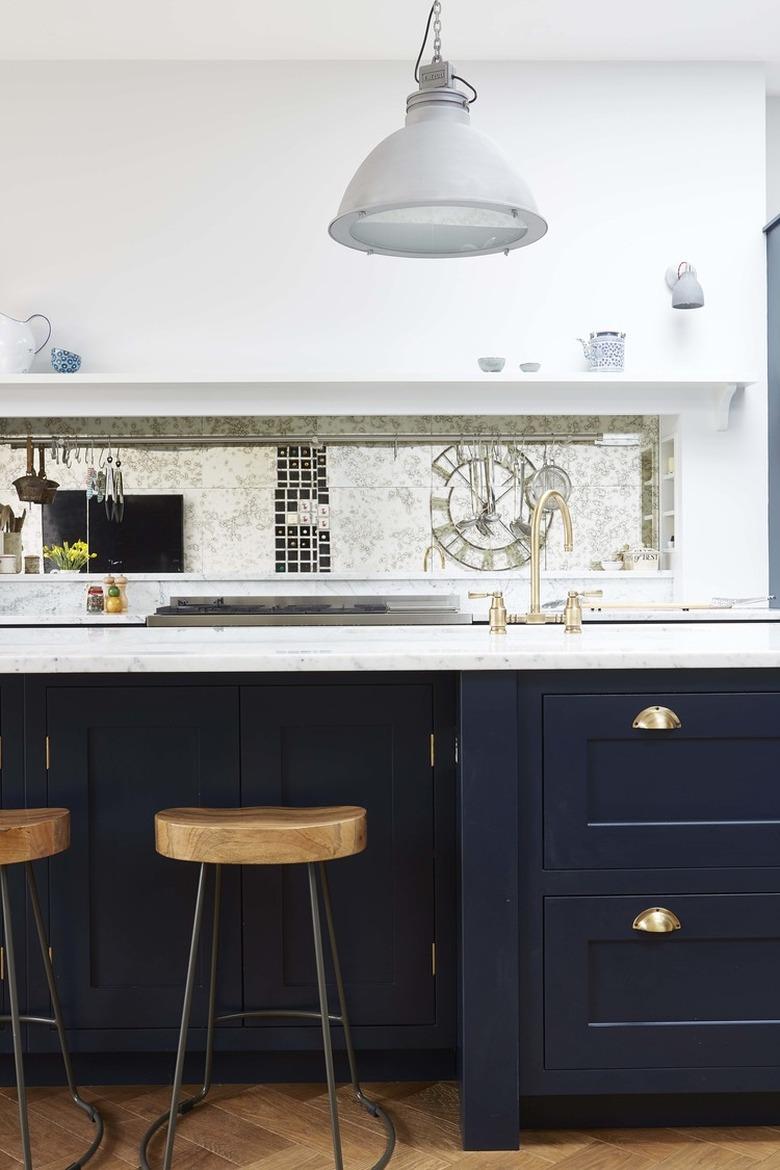 mirror kitchen backsplash with white countertops and blue cabinets