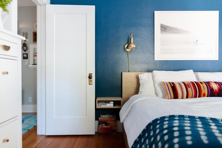 blue bedroom with white door and colorful pillows