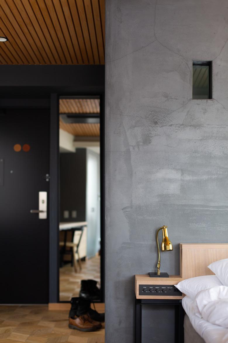 dark minimalist bedroom with gold lamp and rustic wood floor