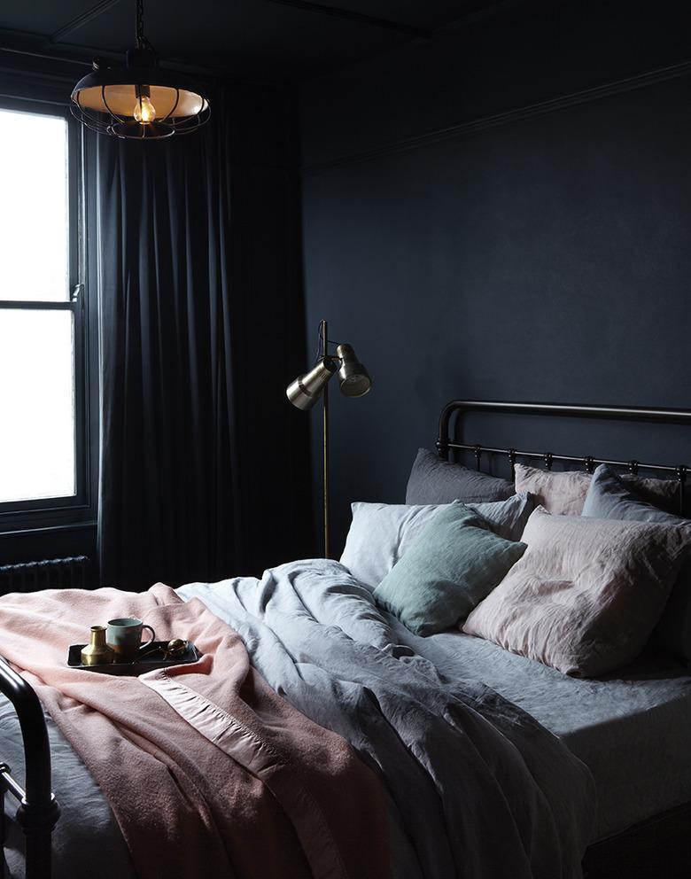 dark minimalist bedroom with seafoam bedding and pink blanket