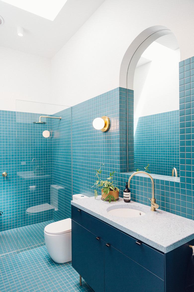 blue tile bathroom with deck-mounted faucet on blue vanity