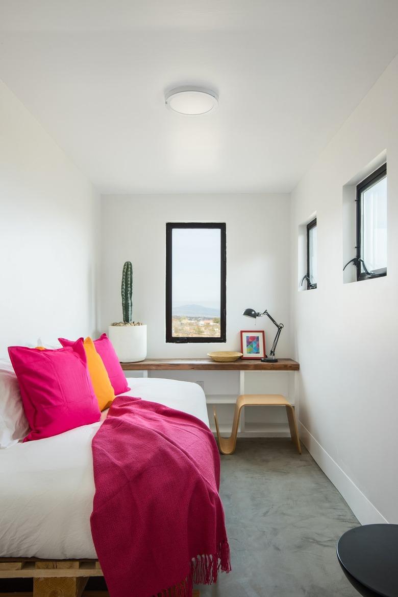 white desert style home office with daybed, built-in desk, and hot pink throw pillows and throws