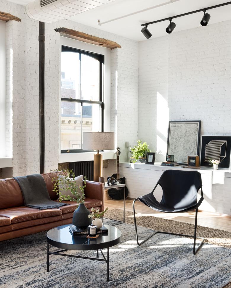 living room with leather furnishings and painted white brick walls