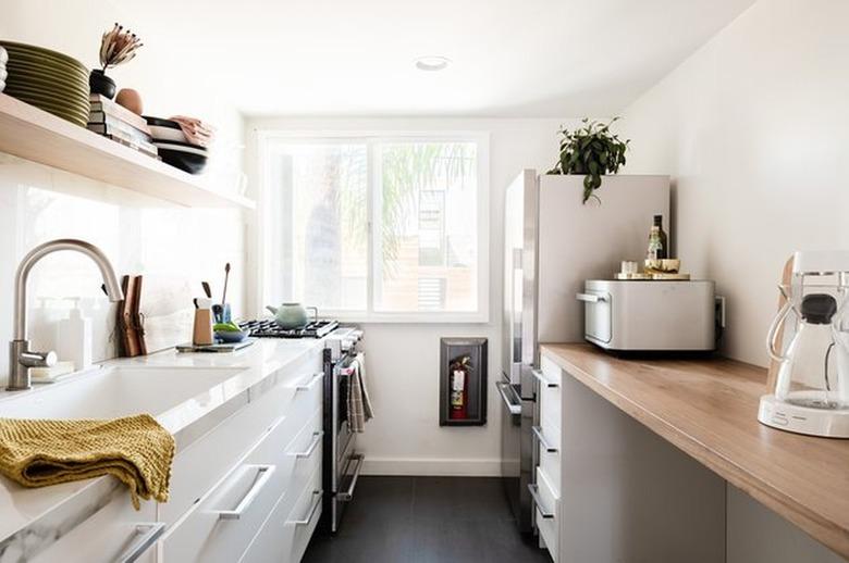 Kitchen with wood countertop white cabinets, open shelf.