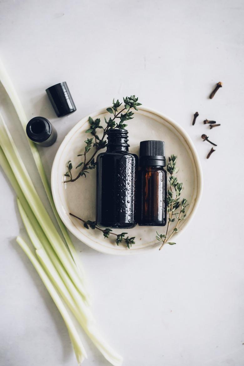 Small beige dish with essential oil glass bottles and herbs