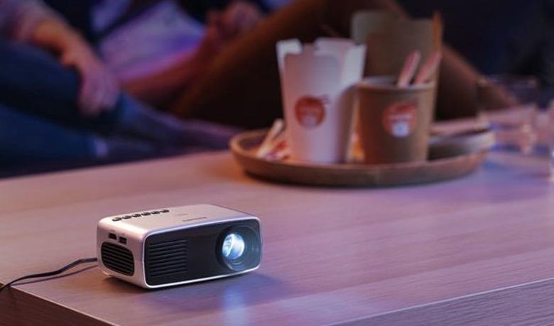 The Philips NeoPix Start Mini Projector on a wooden surface.