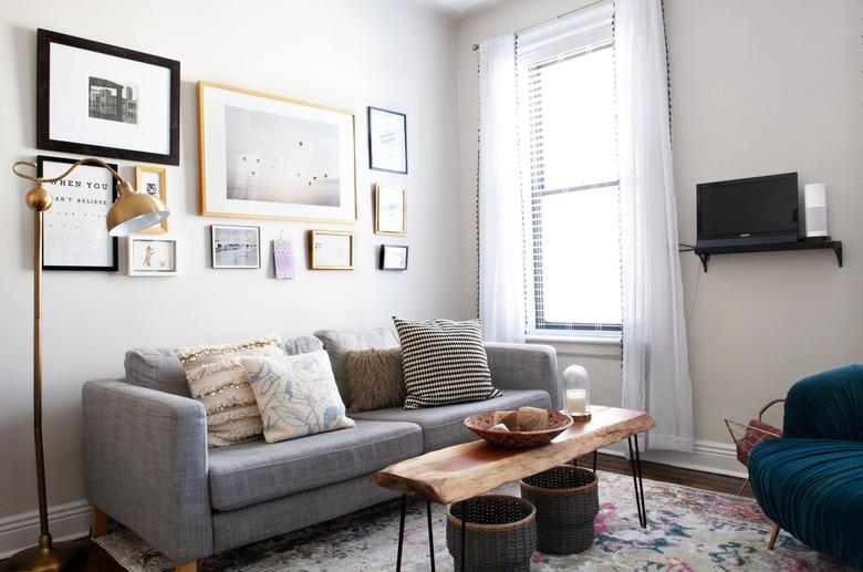 Gray living room sofa with pillows, a rustic wood table and an art wall