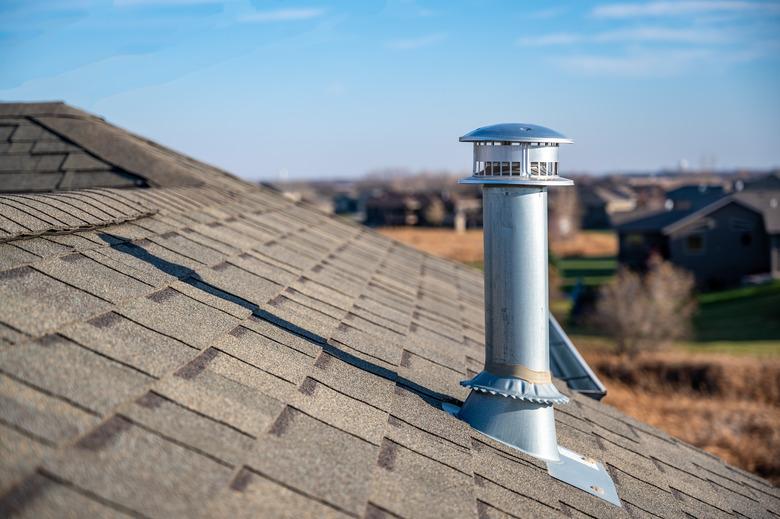 side view of a Galvanized metal chimney exhaust on asphalt roof with a rain cap