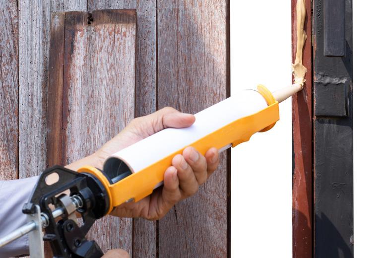 Technician man hand using glue gun with silicone adhesive