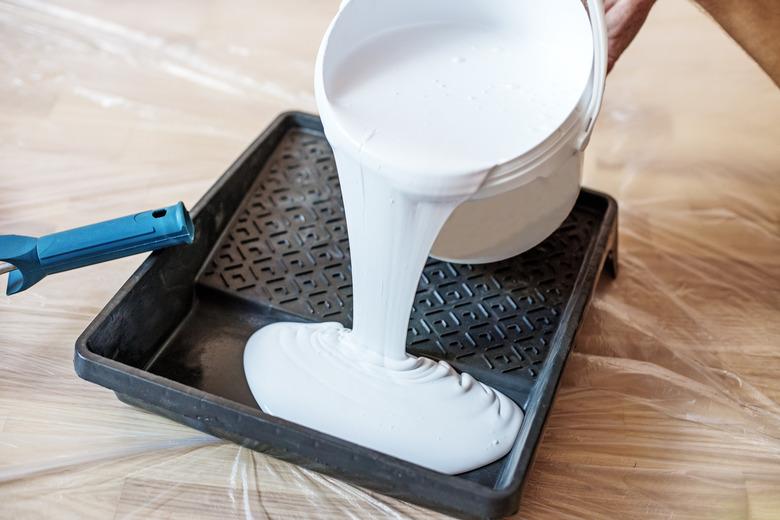 Close up of paint roller in tray. Closeup view of paint tray filled with white paint.