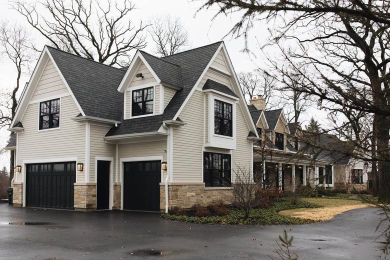 Beige house with a black roof and stone