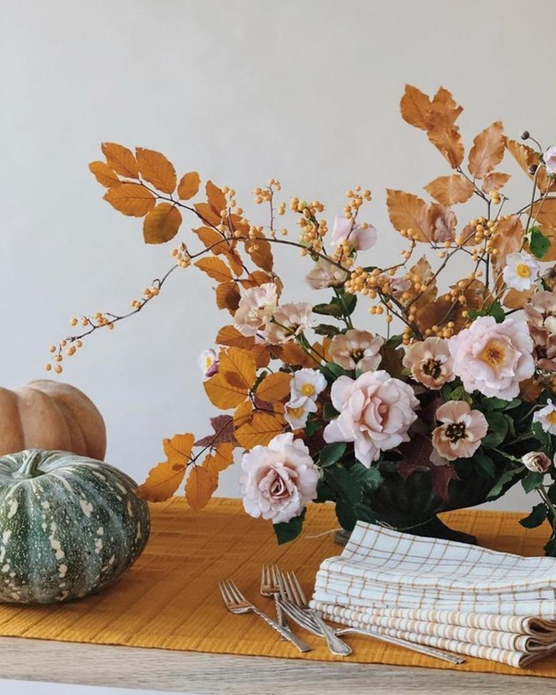 fall kitchen decor with yellow table runner with yellow and pink flower arrangement on top