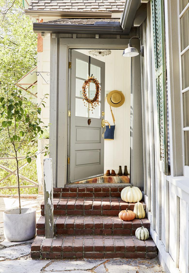 fall porch decor with wreath on door and pumpkins on steps