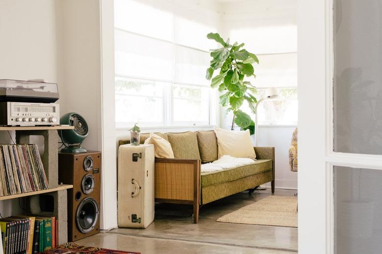 a green mid-century couch with a vintage suitcase for a side table