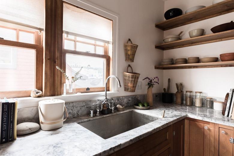 farmhouse sink with grey marble countertops and wood shelves