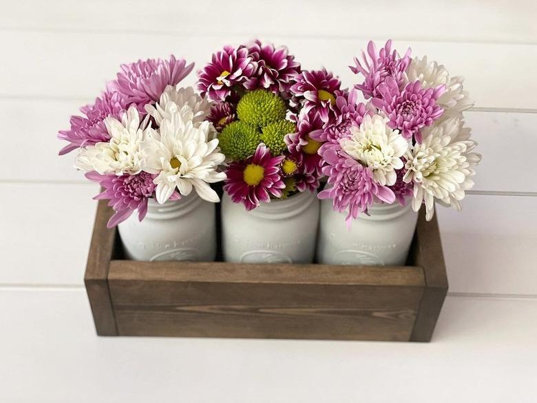 centerpiece with three white mason jar vases in wooden box