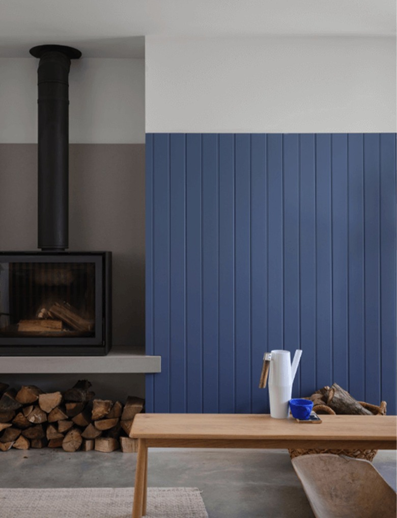 Farrow & Ball's medium blue paint color on the bottom three-quarters of a wall next to a black cast iron fireplace.