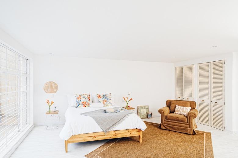 white bedroom with bed, armchair and floor to ceiling windows