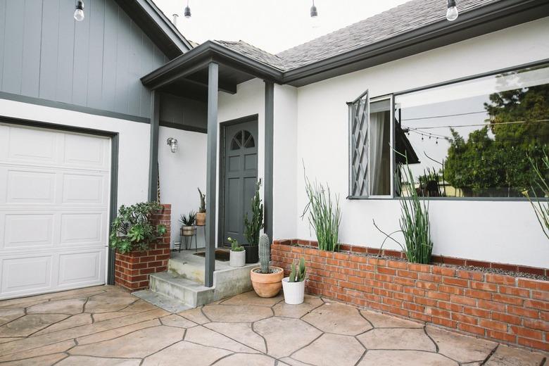 Panel-style white garage door with blue exterior and minimalist landscaping