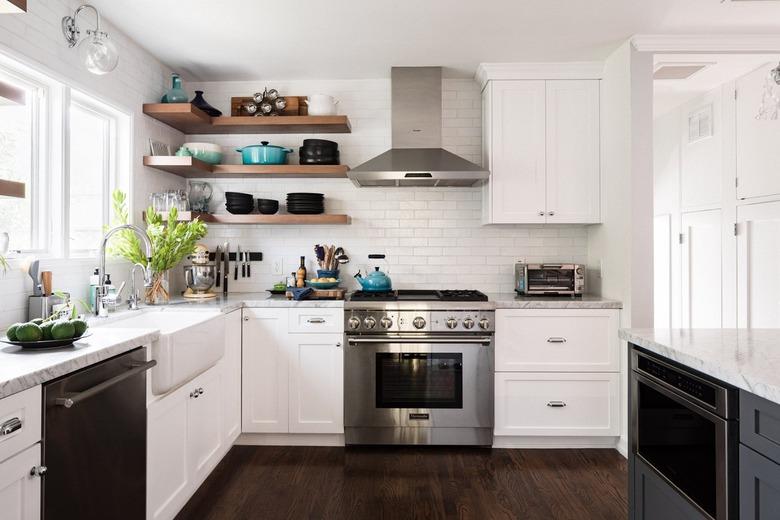 Kitchen with gas range, hood, white cabinets, farmhouse sink, window, open shelves.