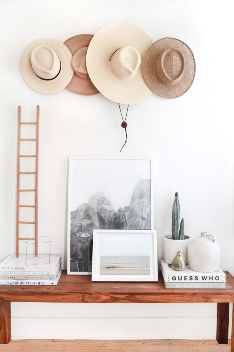 hats hung on wall above decorative table