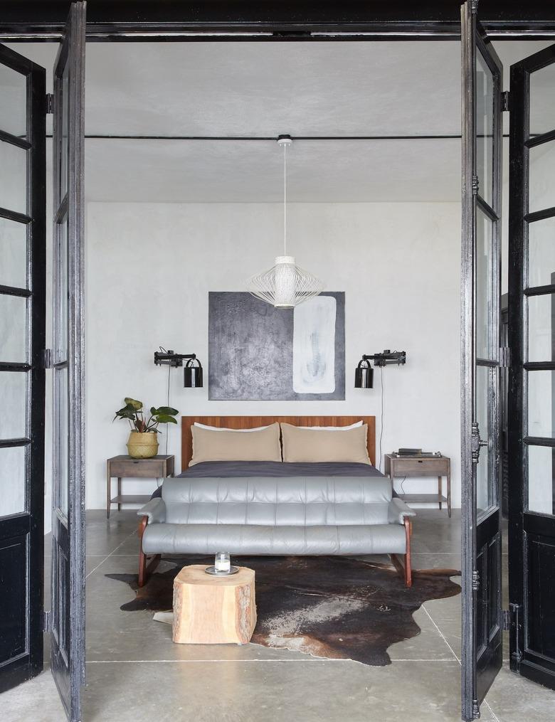 Spacious, industrial bedroom with leather sofa at foot of bed