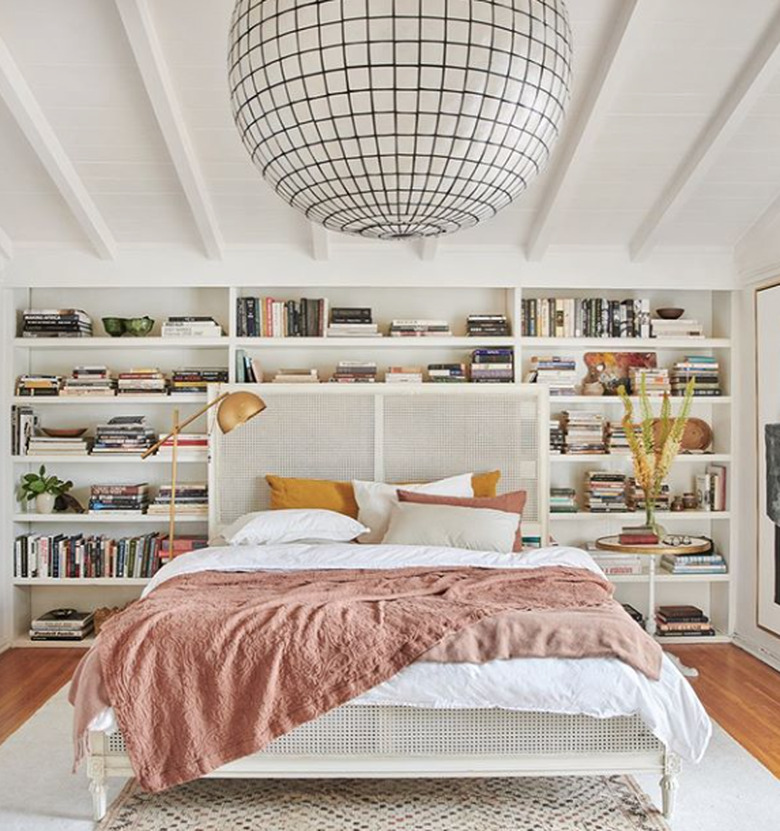 white bedroom with  floor-to-ceiling bookcase and statement chandelier