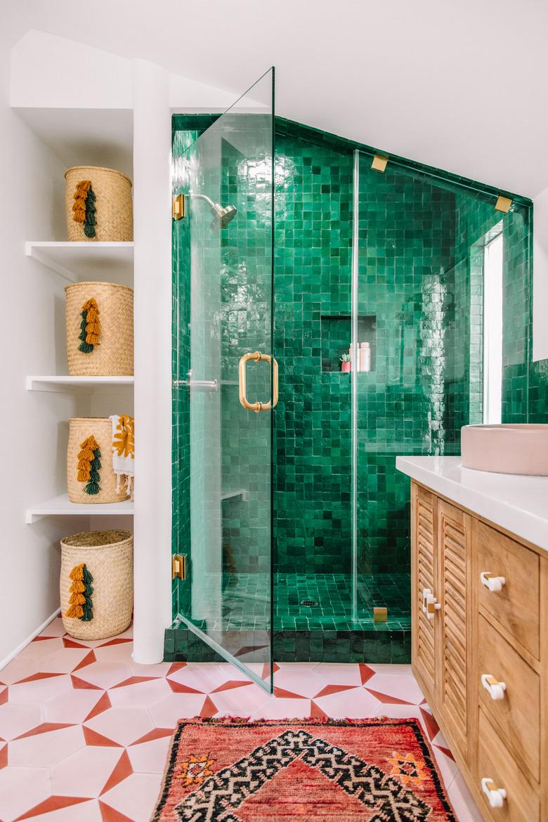 modern bathroom with glass shower door and pink patterned floor tiles and emerald green shower tiles