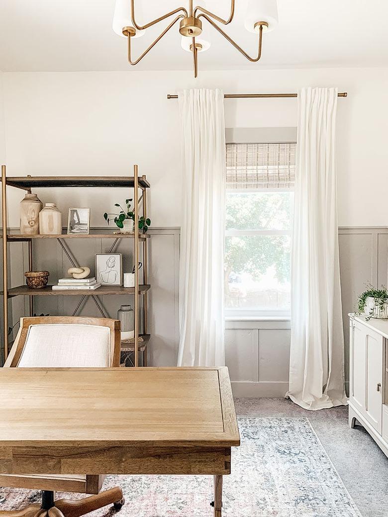 gray home office with gray wainscoting and brass chandelier