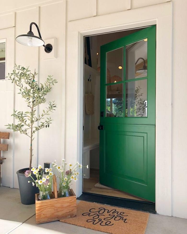 Bright green exterior house paint on front door with white exterior and black barn light