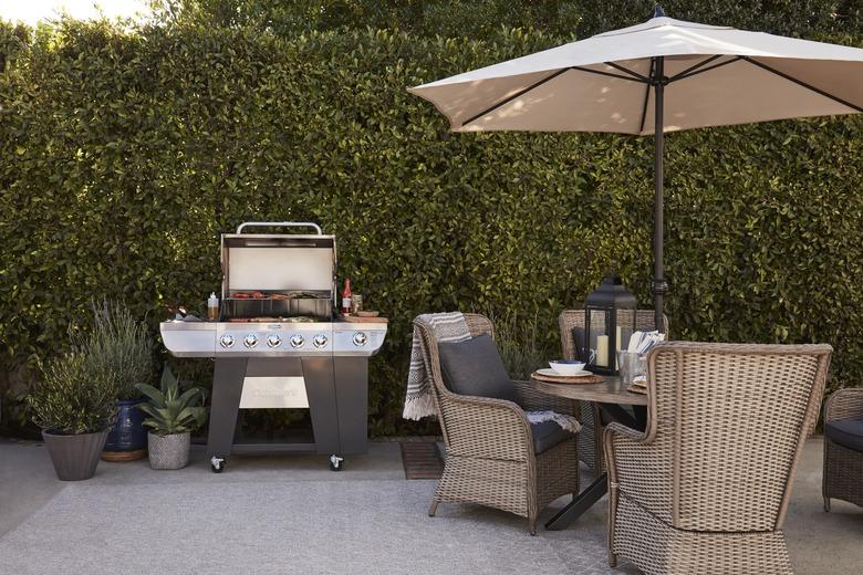 Outdoor grill near dining table and umbrella