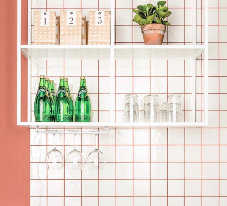 Kitchen with white square tile backsplash, light orange grout, shelves.