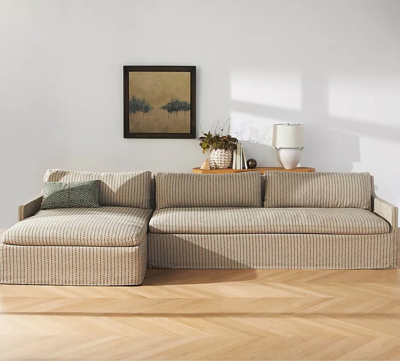 Striped sectional, wood floors, art, lamp.