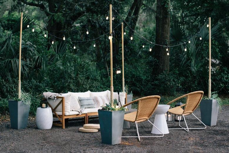 Round wicker chairs, white cushioned sofa, white stool and string lights