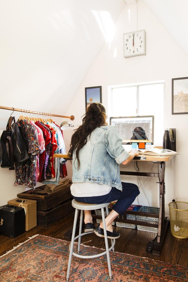 Standing desk inside a closet space with wardrobe rack, clock on wall, area rug with Home Office Desk Ideas