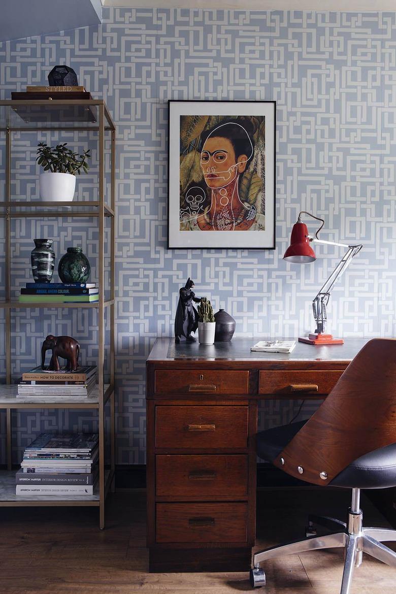 mid century modern home office with farrow and ball enigma wallpaper in blue, portrait of frida khalo hanging above the desk