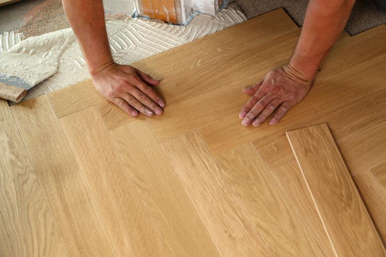 High angle shot of a worker installing wooden parquet laminate flooring