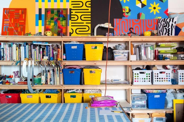 Homeschool Organization with Yellow, red, blue bins on shelves with art supplies, books, art.