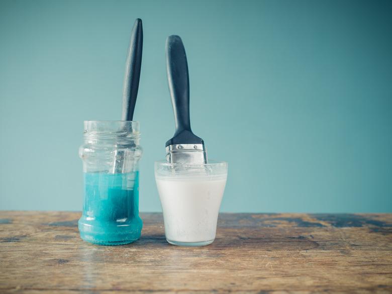 Two paintbrushes soaking in jars.