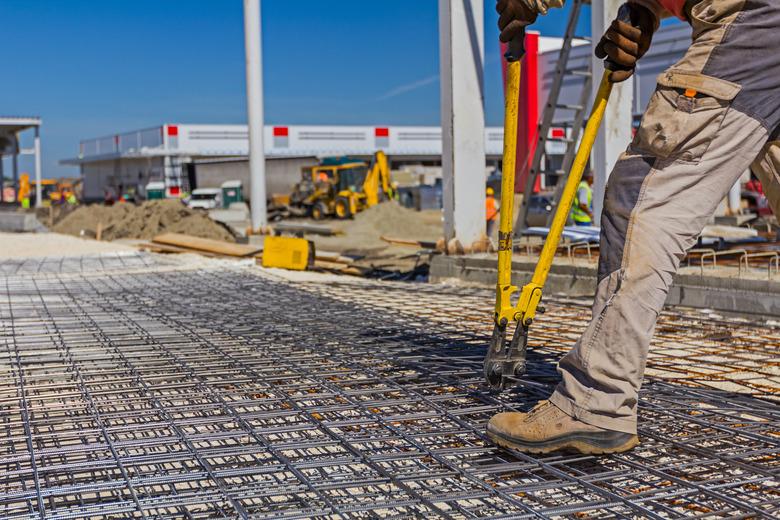 Worker is cutting rebar with scissors for reinforcement bars.