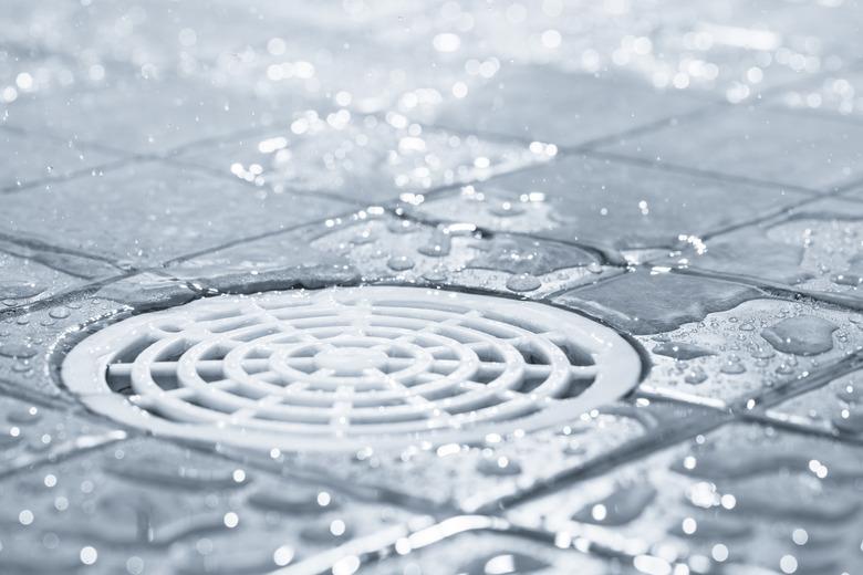 White plastic shower drain with drops of water around it