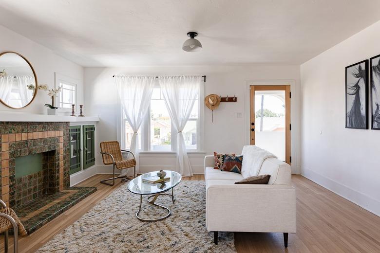 Living room with fireplace, white couch, rug coffee table, mirror.