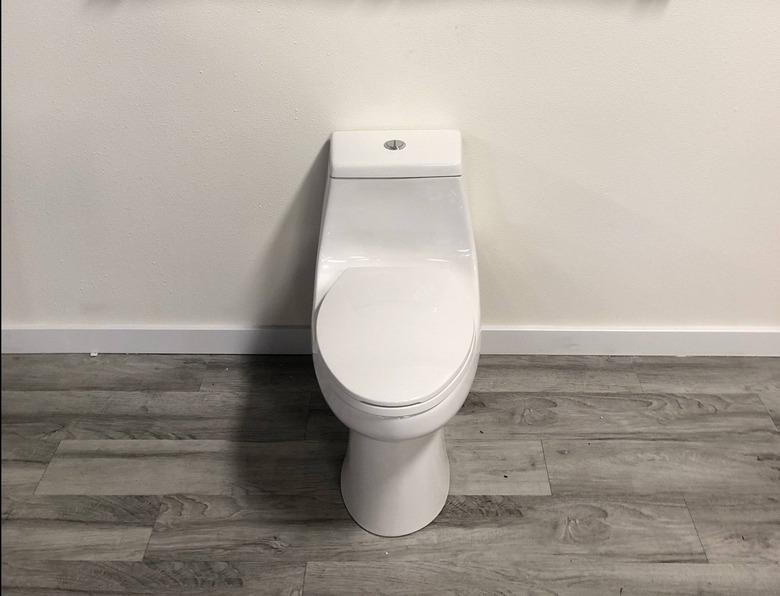 A dual flush toilet on a wood floor