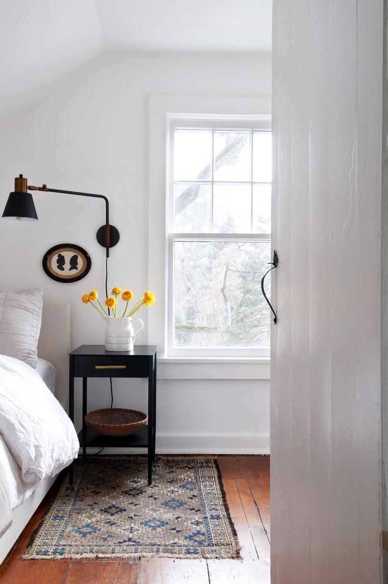 Bedroom with white walls and wood floors with dark farmhouse furnishings