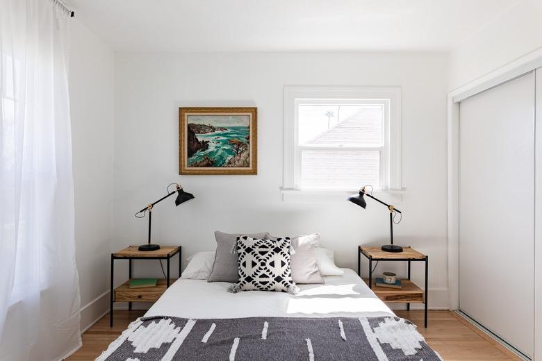 Bedroom with boho pillow and blanket, two side tables with black lamps