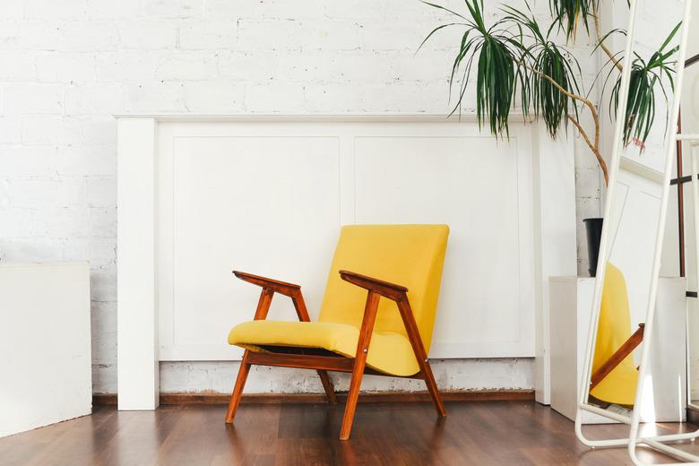 Yellow armchair and indoor plant against a white brick wall.